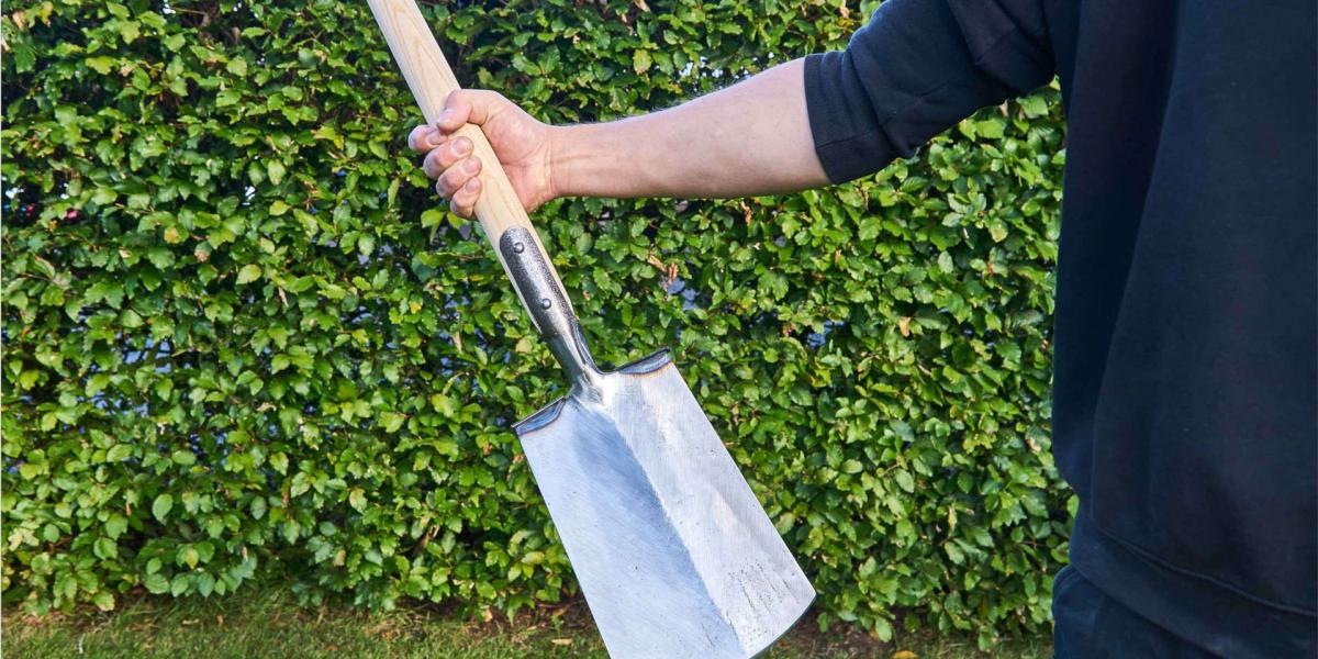 Ein geschmiedeter Spaten in den Händen eines Mannes im Garten von der Manufaktur Baack Spaten